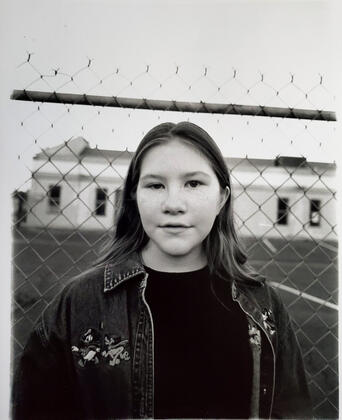 black and white close up of girl in front of a fenced church