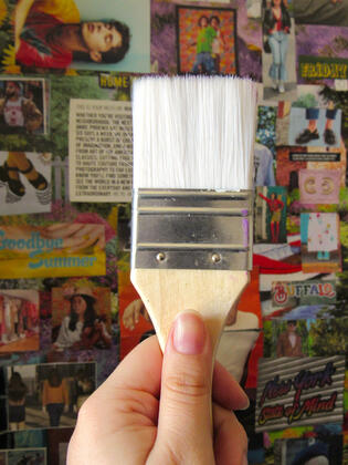 Clean paintbrush held in front of collage of colorful images