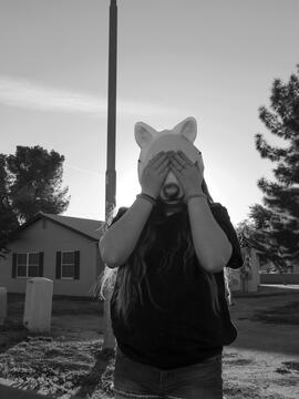 Black and White photo of girl with a wolf mask covering eyes outside